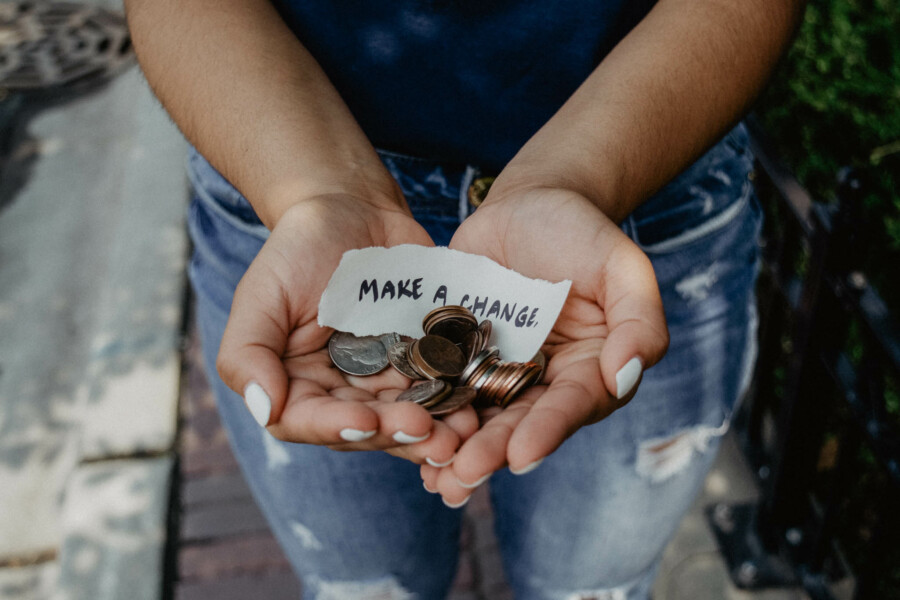 Woman holding coins in her hands with a note that says "Make a Change".